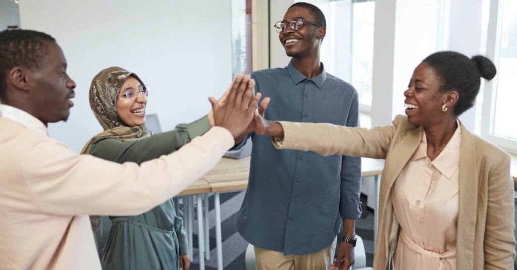 A joyful group of diverse colleagues high-fiving each other in an office, symbolizing teamwork and collaboration.